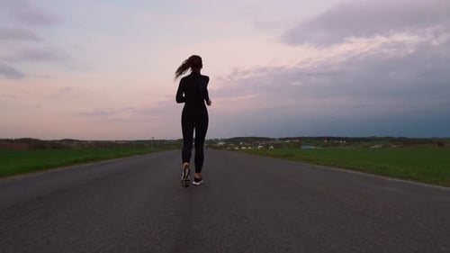 Young Woman Running on a Rural Road During Sunset