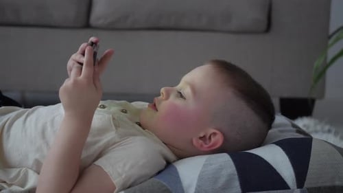Child Lies Down Looking at a Mobile Phone