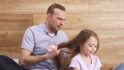 Father Combing Tangled Hair of Daughter at Home