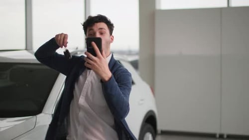 Auto Center Cheerful Man Records Video on a Smartphone Rejoices in Buying a New Car From Automobile