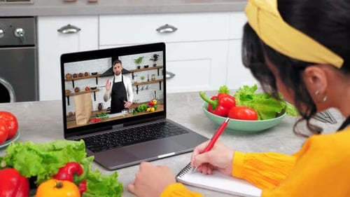 Woman Takes Notes During Cooking Lesson on Laptop