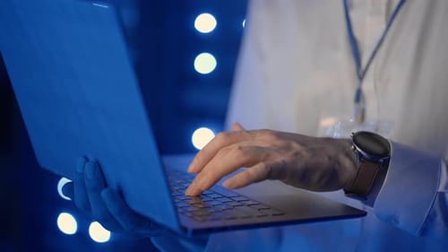 Man Typing on Laptop in Blue Lit Room