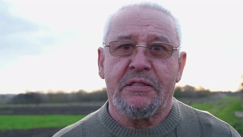 Close-up portrait of a gray-haired elderly man with wrinkles.