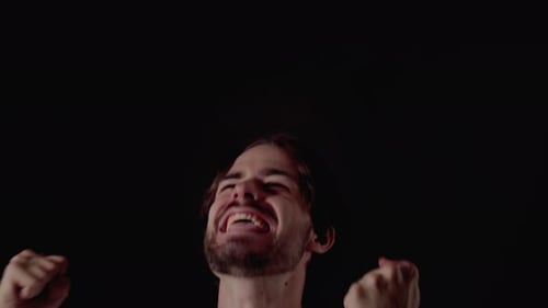 Trendy Young Man being cheerful, excited gestures, close, black background