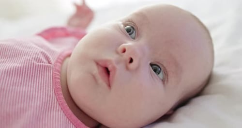 Cute Infant Lying Down on White Blanket Close Up