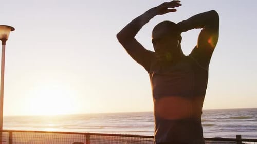 Man Stretching on Beach at Sunrise