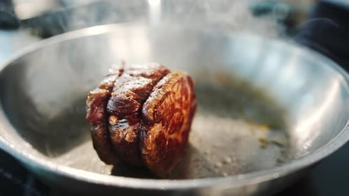 Close-up of a filet mignon being cooked in a frying pan