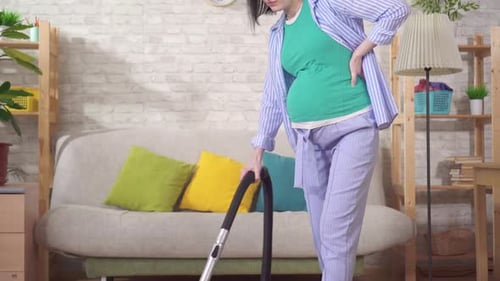 Pregnant Woman Vacuuming the Floor in Her Home