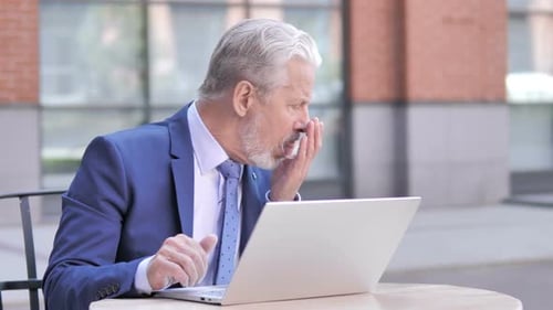 Gray Haired Man Coughing While Working At Laptop
