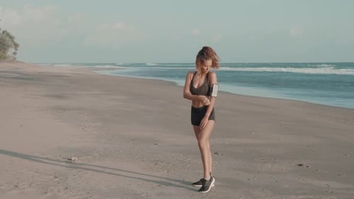 Woman Listens to Music on Sandy Beach