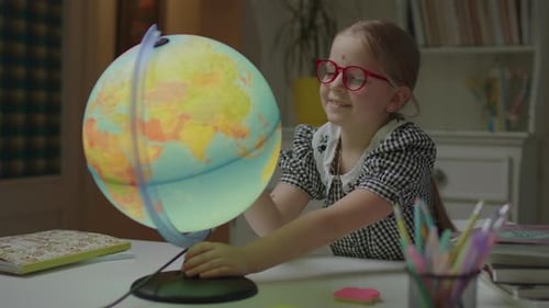Girl Smiles Spinning a Glowing Globe at Her Desk