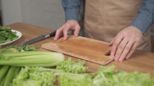 Close up shot of man hands slicing vegetables on wooden cutting board for salad on the table