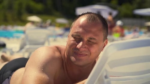 Un homme en gros plan est allongé sur une chaise longue sur la plage Athletic Physique