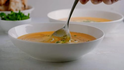 Delicious orange soup is stirred with a spoon