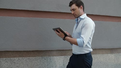 Young Man Celebrates with Tablet on Urban Sidewalk