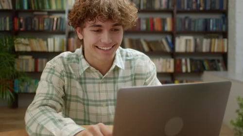 Smiling Young Adult Works on Laptop at Desk