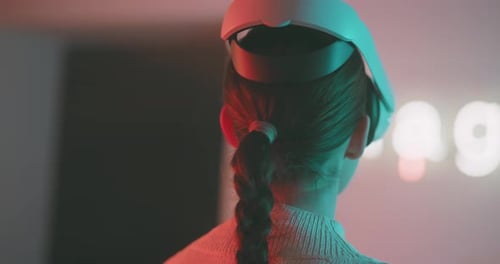 Close up of young woman in vr goggles looking around in blue neon lights