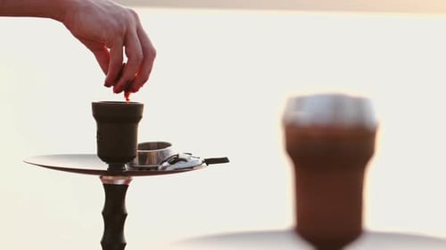 Hand Preparing Hookah on Reflective Surface