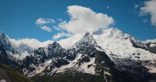 Air Flight Through Mountain Clouds Over Beautiful Snowcapped Peaks of Mountains and Glaciers