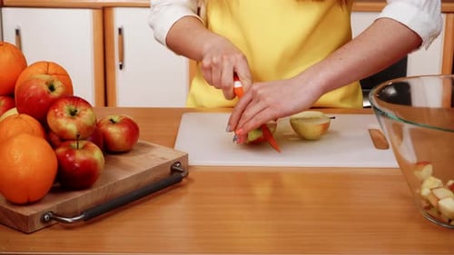 Woman Cuts Apple on Cutting Board in Kitchen