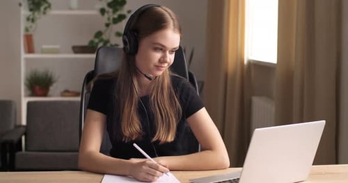 Friendly Caucasian High School University Female Student Wears Headphones and Concentrating on Work