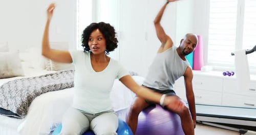 Couple Stretching on Exercise Balls in Bedroom