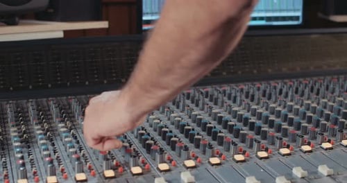 Sound engineer working in a recording studio with a sound console and microphones