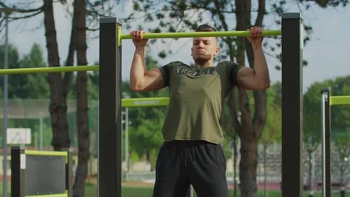Muscular Man Does Pull-Ups at Outdoor Gym