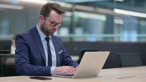 Man Typing on Laptop in Modern Office