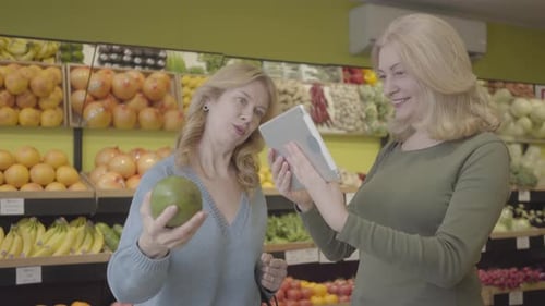 Women Shop for Fruit in Supermarket with Tablet