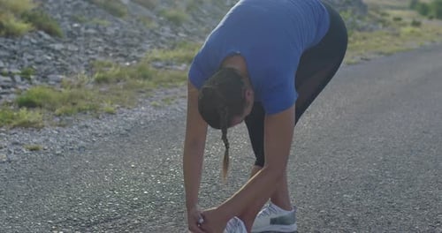Young Woman Stretching Hamstring Outdoors on Rural Road