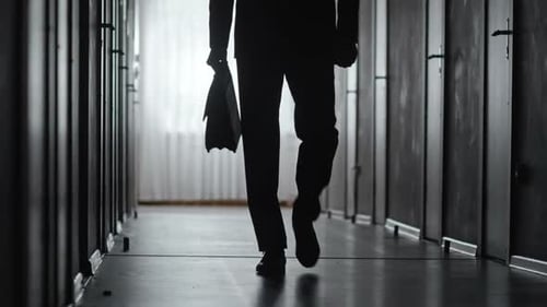 Silhouette of Man Walking Down Dark Hallway