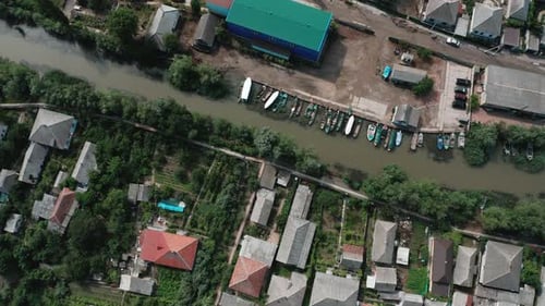 Rotating Aerial Top View of Boats Docked at the Bank of a Small River in the Village