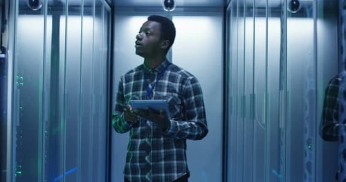 Technician Inspecting Servers With Tablet in Data Center