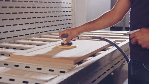 Slow motion of a worker polishing a cabinet door in a furniture factory