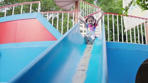4K Little Asian girl sliding and playing at playground in the park