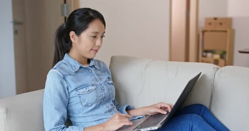 Woman Using Laptop Computer at Home on Sofa