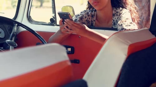 Woman Using Mobile Phone in a Vintage Van