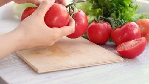Hands Cutting a Fresh Red Tomato for Salad