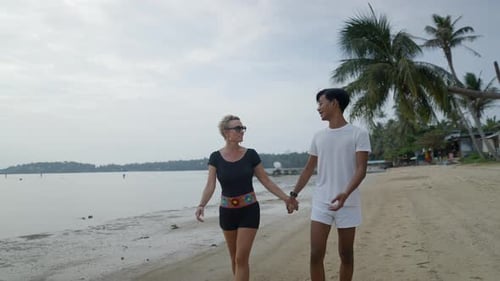 Couple Walks Hand in Hand on Tropical Beach