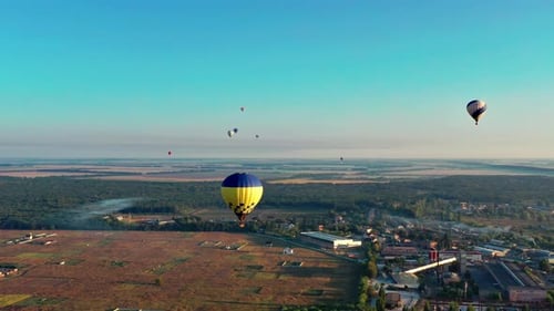 Multicolored balloons fly over trees. Nice top view of the park, forest covered with greenery.