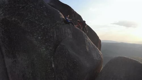 A Pair of Climbers Climb the Mountain. A Man Insures a Woman with a Rope, a Woman Climbs the Rock