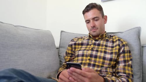 Man Relaxing on Couch Using Phone