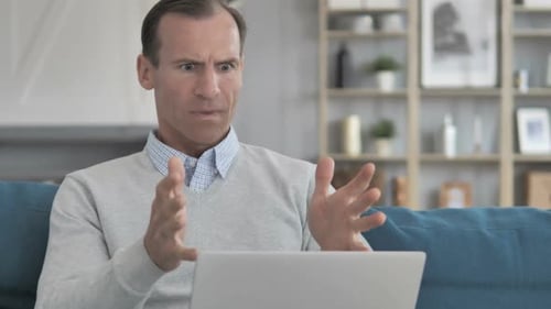 Man Frustrated Using Laptop on Couch at Home