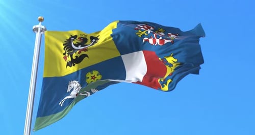 Waving Flag with Heraldic Emblems Against a Clear Blue Sky