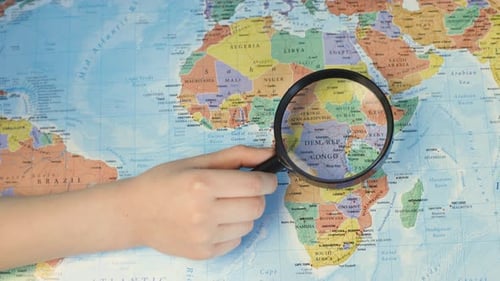 Magnifying Glass Inspects Africa on Colorful World Map