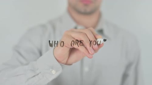 Person Writes "Who Are You?" On Glass