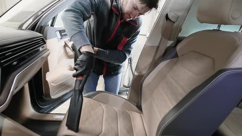 Man Cleaning Car Seat with Vacuum Cleaner