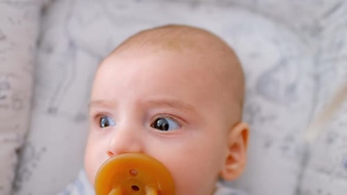 Hand der Mutter streichelt ihr süßes Baby, das zu Hause mit Schnuller in der Krippe liegt 4k