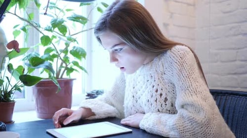 Woman Looks at Tablet and Reacts Happily Indoors